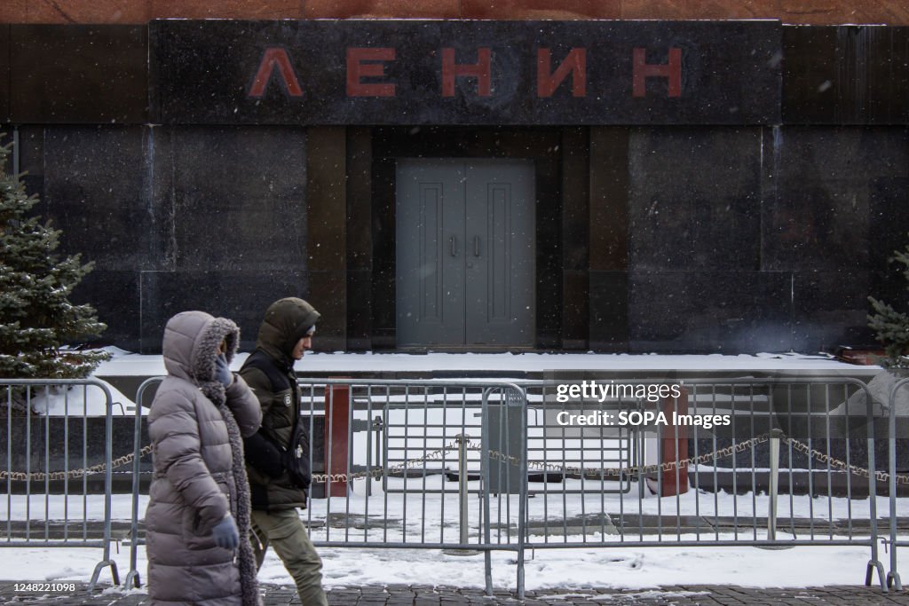 People walk by Lenin's mausoleum on the Red Square in Moscow...