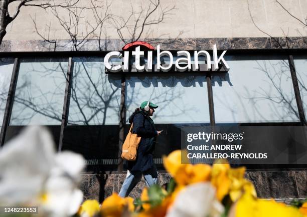 Woman walks past a Citibank branch in Washington, DC, on March 14, 2023. - Wall Street stocks advanced early Tuesday, driven by a bounce in beaten...