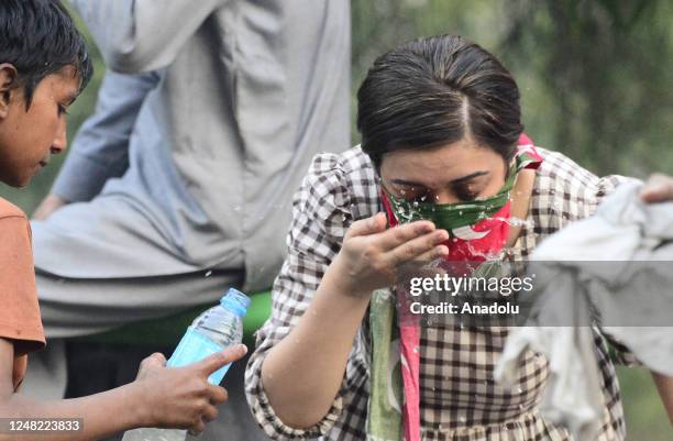 Woman is affected from tear gas as supporters of Pakistan's former Prime Minister Imran Khan protest after Khan's residence was besieged to arrest...