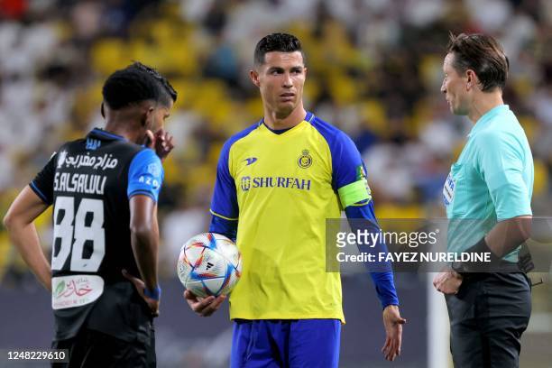 Nassr's Portuguese forward Cristiano Ronaldo holds the ball as he speaks with Abha's Saudi midfielder Saad Al-Selouli and Latvian match referee...
