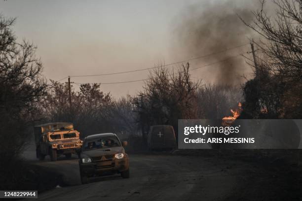 Ukrainian military vehicles drive past a burning land, after white phosphorus munitions exploded in the air, at the village of Chasiv Yar near...