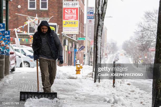 Worker clears snow from the sidewalk in Worcester, Massachusetts on March 14, 2023. - A major Nor'easter is expected to bring heavy snow and strong...