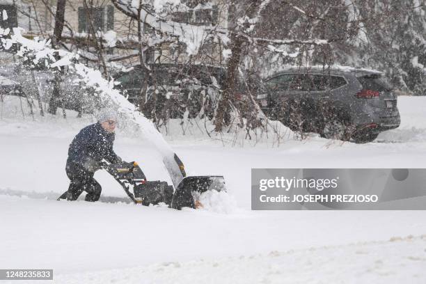 Person tries to use a snowblower to clear snow from their driveway, over a foot deep, during a noreaster in Rutland, Massachusetts on March 14, 2023....