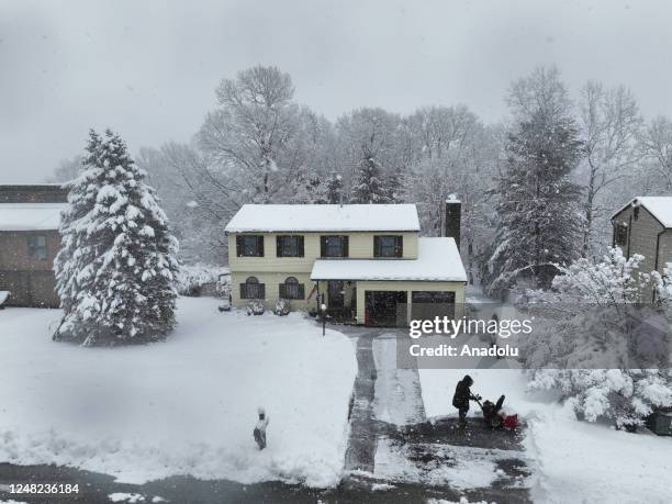 View of heavy snowfall while a resident is trying to remove snow out of house entrances in Harriman, New York on March 14, 2023.