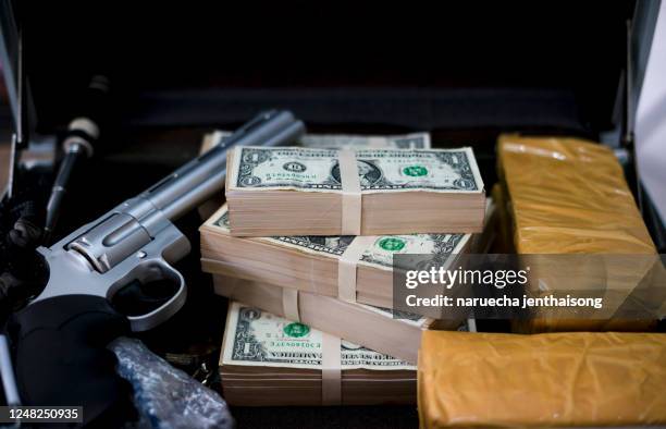 gun with bullets lying on the table. criminal problems. drugs and money on black background. illegal selling. - organized crime stock-fotos und bilder