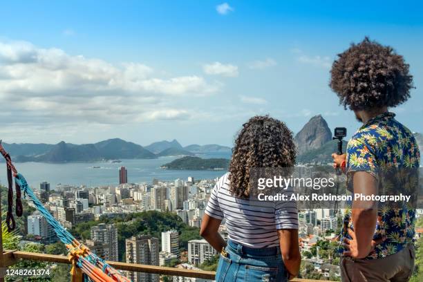 a mixed race african american and latin couple taking pictures of the rio de janeiro skyline from a viewpoint - brazil skyline stock pictures, royalty-free photos & images