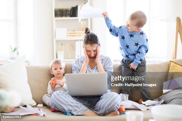 stressed and frustrated mother with two small children in pajams working in home office, quarantine concept. - frustrazione foto e immagini stock