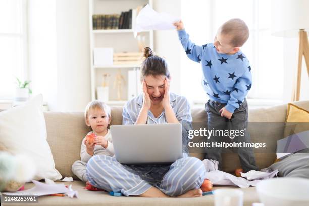 stressed and frustrated mother with two small children in pajams working in home office, quarantine concept. - frustrated parent stock pictures, royalty-free photos & images