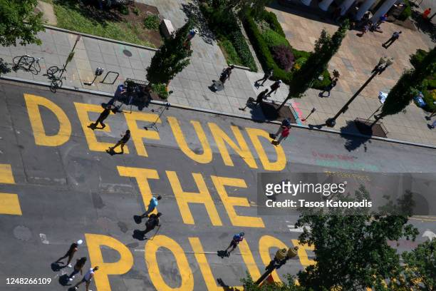 People walk down 16th street after “Defund The Police” was painted on the street near the White House on June 08, 2020 in Washington, DC. After days...