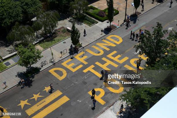 People walk down 16th street after “Defund The Police” was painted on the street near the White House on June 08, 2020 in Washington, DC. After days...