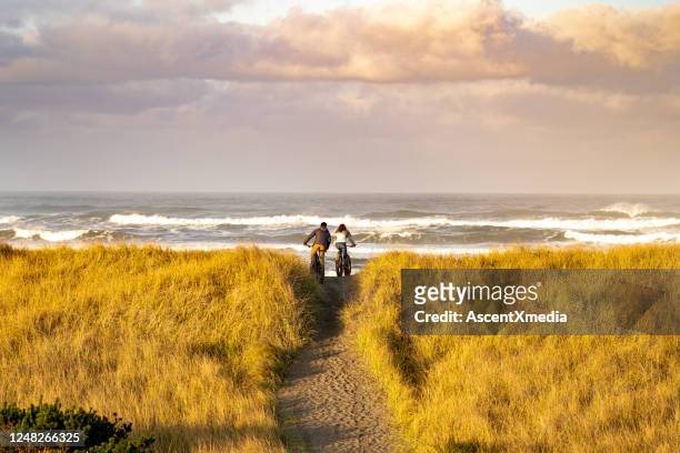 young couple ride fat bikes on coastal trail - washington state stock pictures, royalty-free photos & images