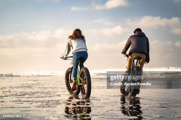 年輕夫婦騎脂肪自行車在海灘上,潮汐公寓 - fat guy on beach 個照片及圖片檔