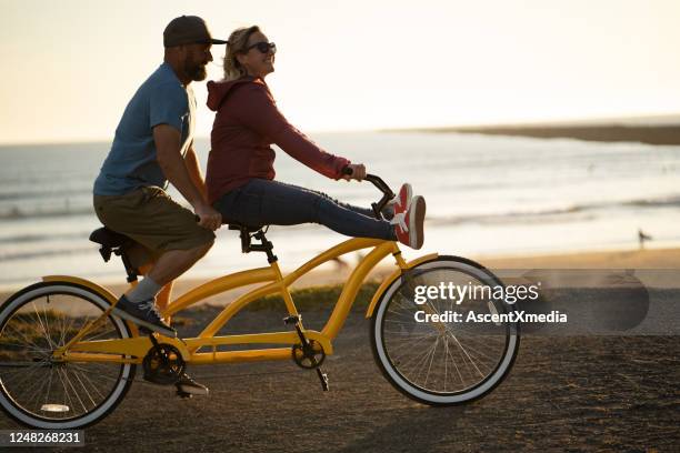 junges paar fährt tandem-bike bei sonnenaufgang - tandem position stock-fotos und bilder