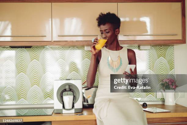 jonge vrouw thuis - woman drinking phone kitchen stockfoto's en -beelden