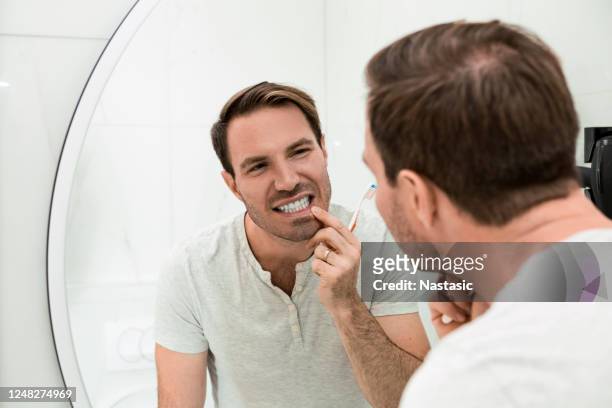 young man brushing teeth in the bathroom - teeth whitening stock pictures, royalty-free photos & images