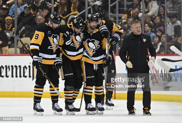 Jan Rutta of the Pittsburgh Penguins is helped off the ice following a possible injury by Brian Dumoulin and Jason Zucker along with trainer Chris...