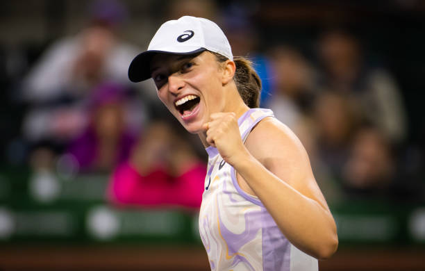 Iga Swiatek of Poland reacts to defeating Emma Raducanu of Great Britain in her fourth-round match on Day 9 of the 2023 BNP Paribas Open at the...
