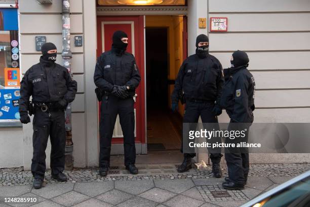 March 2023, Berlin: Police officers stand at an entrance door of a building in Berlin during a raid. Police in Berlin and Saxony-Anhalt have launched...