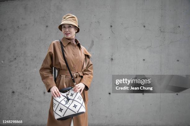 Guest wears a LIE trench coat and a Louis Vuitton Bag at Seoul Fashion Week AW 23 on March 15, 2023 in Seoul, South Korea.