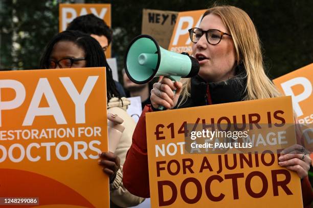 Demonstrator speaks in a loud hailer as she holds a placard during a protest by junior doctors, amid a dispute with the government over pay, outside...