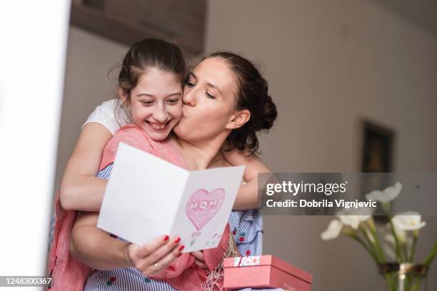woman reading mother's day card and kissing daughter - birthday card stock pictures, royalty-free photos & images
