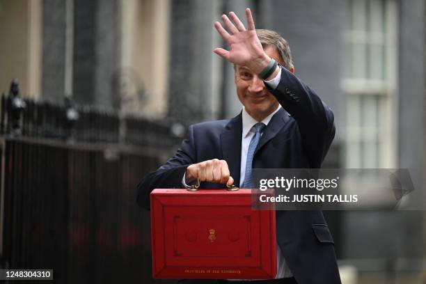 Britain's Chancellor of the Exchequer Jeremy Hunt waves as he poses with the red Budget Box as he leaves 11 Downing Street in central London on March...