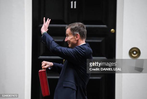 Britain's Chancellor of the Exchequer Jeremy Hunt waves as he poses with the red Budget Box as he leaves 11 Downing Street in central London on March...