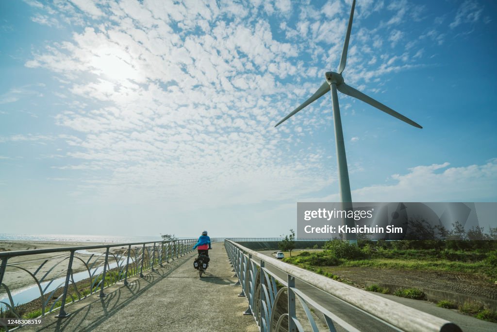 Cyclist passing by wind turbine