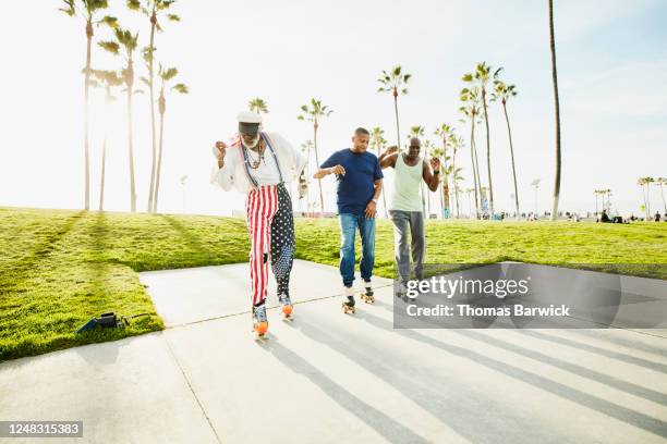 senior and mature friends roller skating together in park - roller skating in park stock pictures, royalty-free photos & images