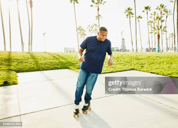 mature man roller skating in park - control pants foto e immagini stock