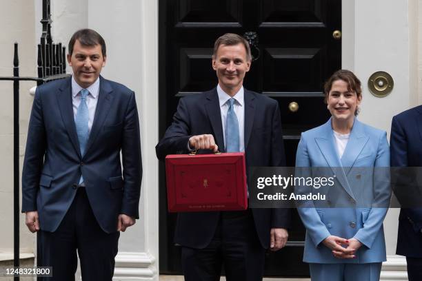 Britain's Chancellor of the Exchequer Jeremy Hunt holds the Budget box as he stands outside 11 Downing Street with his Treasury team members, Chief...