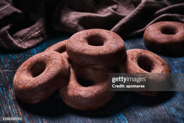 close-upbeeld van een donut zoals chocoladekoekjes. ouderwetse stijl op een blauwachtige rustieke lijst - chocoladedonut stockfoto's en -beelden