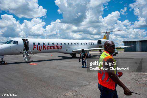 Tourist passenger on the apron of Katima Mulilo Airport disembarking from a FlyNamibia aircraft as a member of the ground staff walks by.