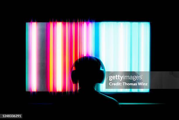 silhouetted person with headphones watching large tv screen - insight tv stockfoto's en -beelden