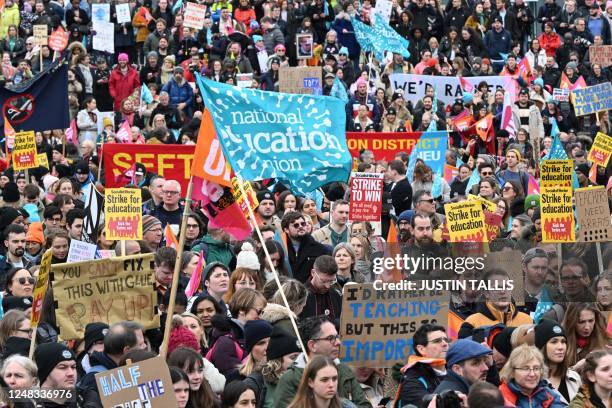 Demonstrators hold placards, flags and chant slogans as they take part in a protest called by different British trade unions amid a dispute with the...