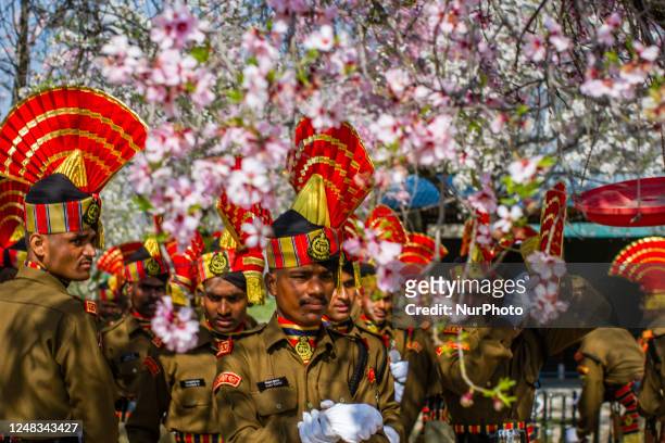 Indian Border Security Force soldier stand next to the blooming almond blossom after their passing out parade at a garrison on March 15, 2023 in...