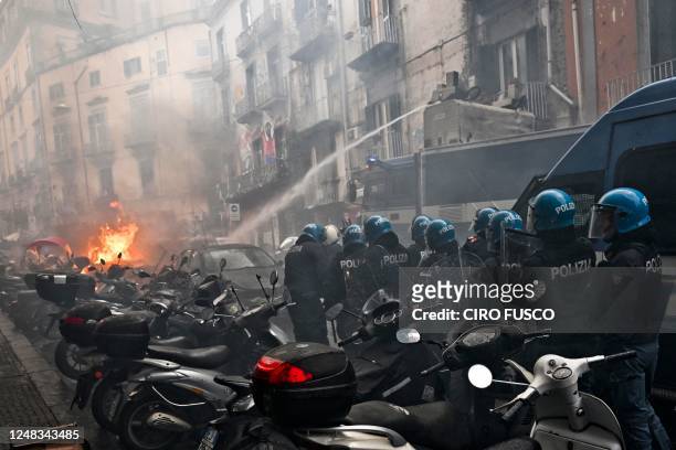 This photo obtained from Italian news agency Ansa shows a anti-riot policemen move beside a truck extinguishing the blaze of a police car after it...
