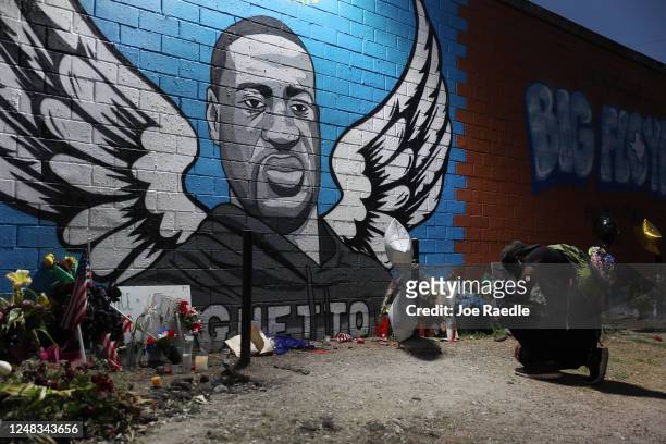 Joshua Broussard kneels in front of a memorial and mural that honors George Floyd at the Scott Food Mart corner store in Houston's Third Ward where...