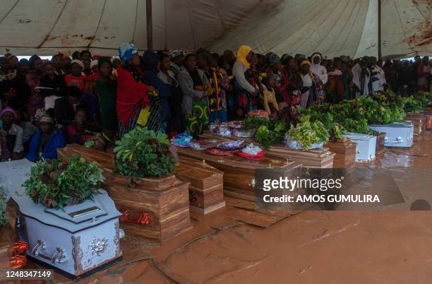 Mourners stand behind coffins of their relatives during a mass funeral for mudslide victims at Chilobwe townships Naotcha Primary school camp in...