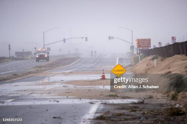 Huntington Beach, CA A California Department of Transportation worker patrols with a view of both sides of the closed Pacific Coast Highway, due to...