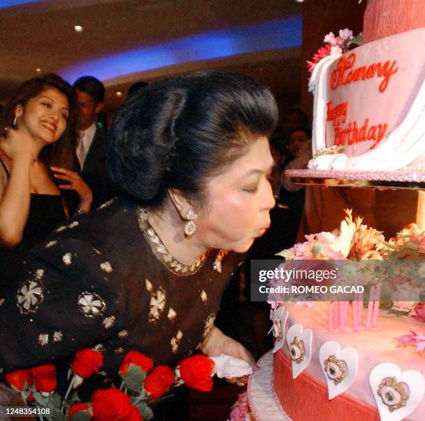 Former first lady Imelda Marcos blows candles on a 10 feet high birthday cake during a party late 02 July 2002 at a Manila hotel celebrating her 73...