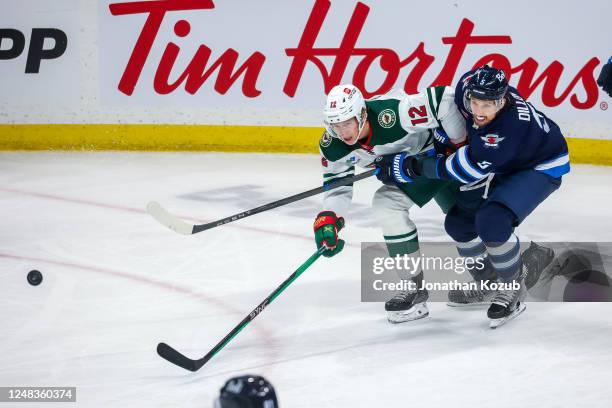 Matt Boldy of the Minnesota Wild and Brenden Dillon of the Winnipeg Jets chase the puck during first period action at Canada Life Centre on March 08,...