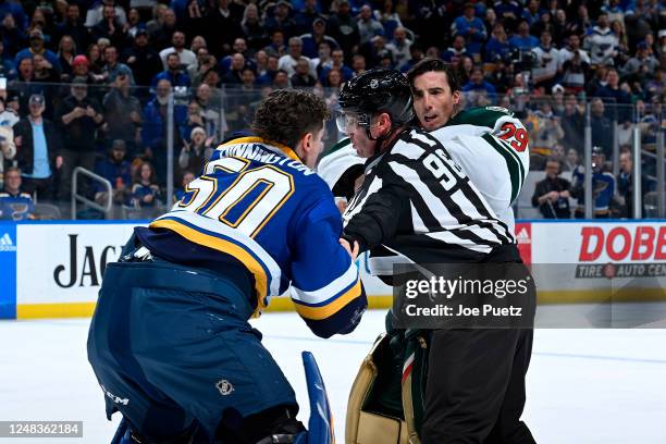 Marc-Andre Fleury of the Minnesota Wild attempts to get physical with Jordan Binnington of the St. Louis Blues but is stopped by linesman Dan Kelly...