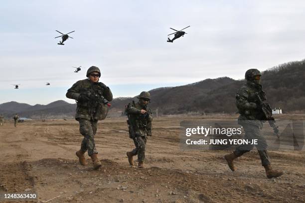 South Korean soldiers move to a position as US Army UH-60 Black Hawk helicopters fly overhead during a South Korea-US joint drill at a military...