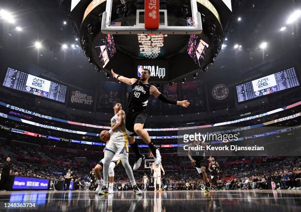 Ivica Zubac of the Los Angeles Clippers defends Jordan Poole of the Golden State Warriors during the second half at Crypto.com Arena on March 15,...