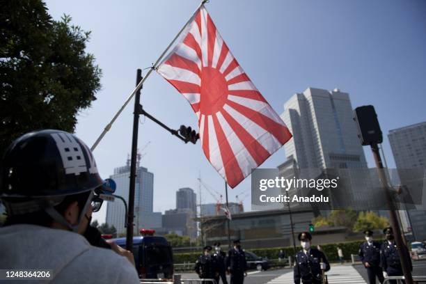 Member of nationalist group wave the Japanese Rising Sun Flag face to police officers in front of the Prime Minister office on March 16 in Tokyo,...