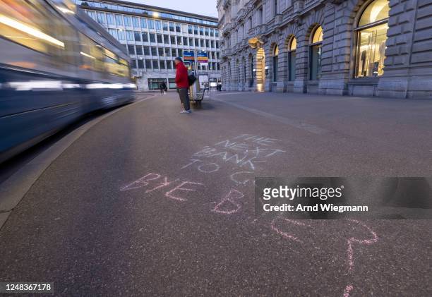 Slogan is written on the sidewalk in front of the global headquarters of Swiss bank Credit Suisse the day after its shares dropped approximately 30%...