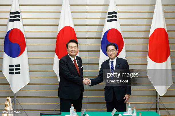 Yoon Suk Yeol, South Korea's president, left, and Fumio Kishida, Japan's prime minister, shake hands ahead of a summit meeting at the prime...