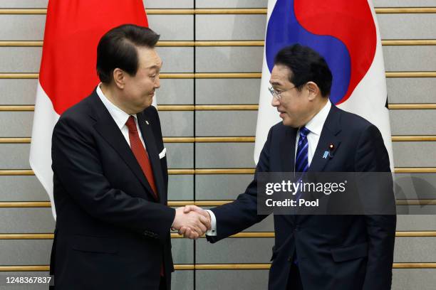 Yoon Suk Yeol, South Korea's president, left, and Fumio Kishida, Japan's prime minister, shake hands ahead of a summit meeting at the prime...