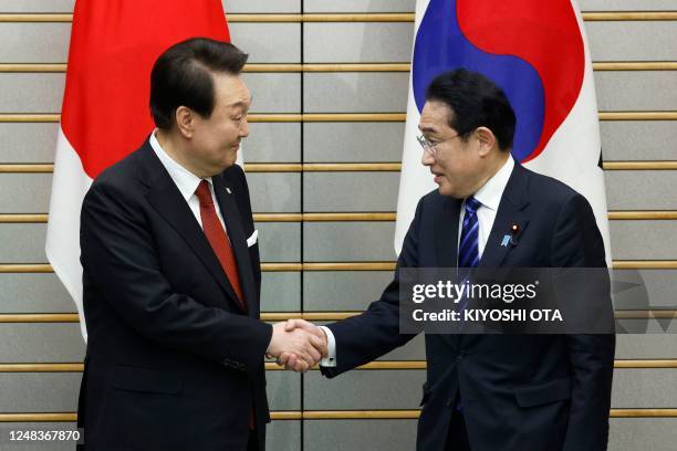 South Korea's President Yoon Suk Yeol and Japan's Prime Minister Fumio Kishida shake hands ahead of a summit meeting at the prime minister's official...